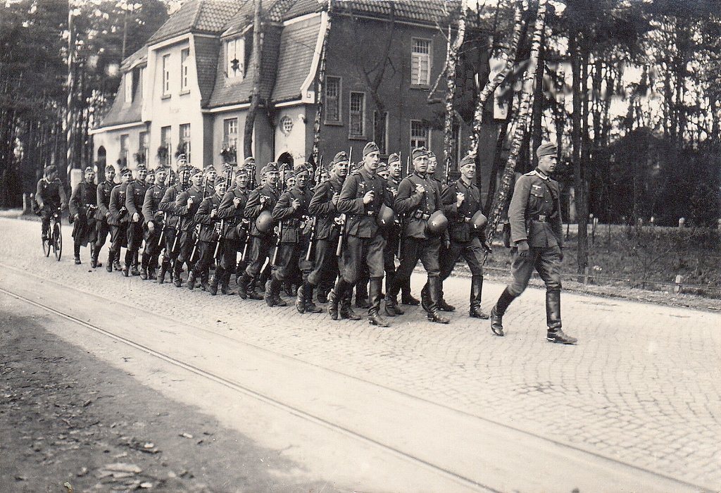  Wehrmachtssoldaten marschieren die Strase entlang.jpg. 