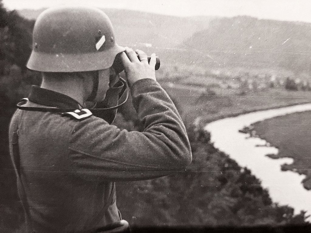  Wehrmachtssoldat, der durch ein Fernglas schaut.jpg. 